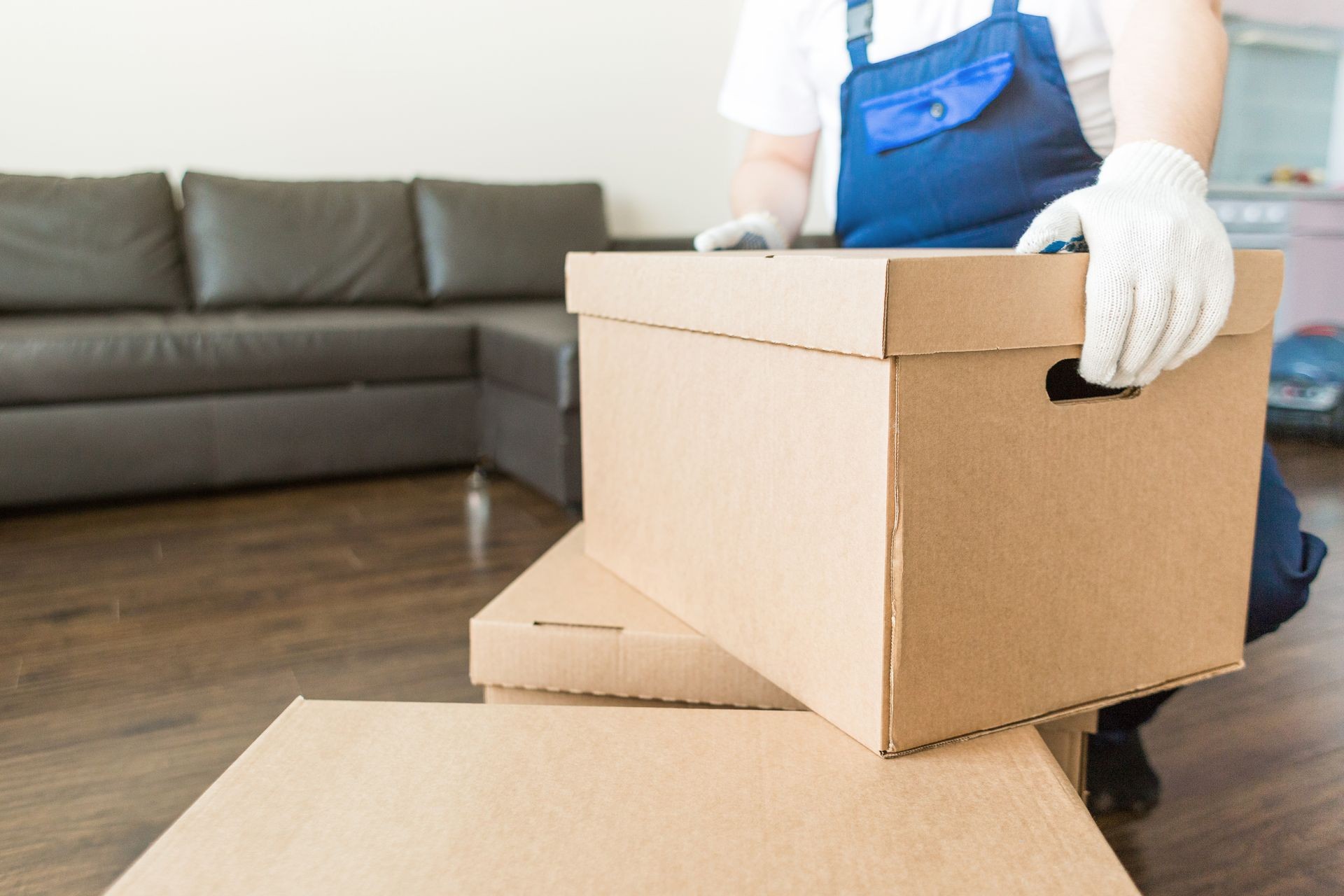 Delivery man loading cardboard boxes for moving to an apartment. professional worker of transportation, male loaders in overalls